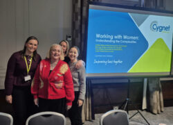 Colleagues and a service user from Cygnet Maple House standing beside a presentation screen titled ‘Working with Women: Understanding the Complexities’ at the Female Collaboration Day event.