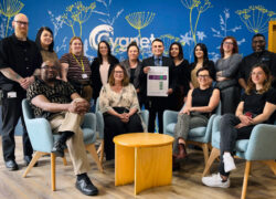 The Cygnet Hospital Sheffield team pose in the reception celebrating their recent CQC success. A man in the middle of the group holds a printout of the results.