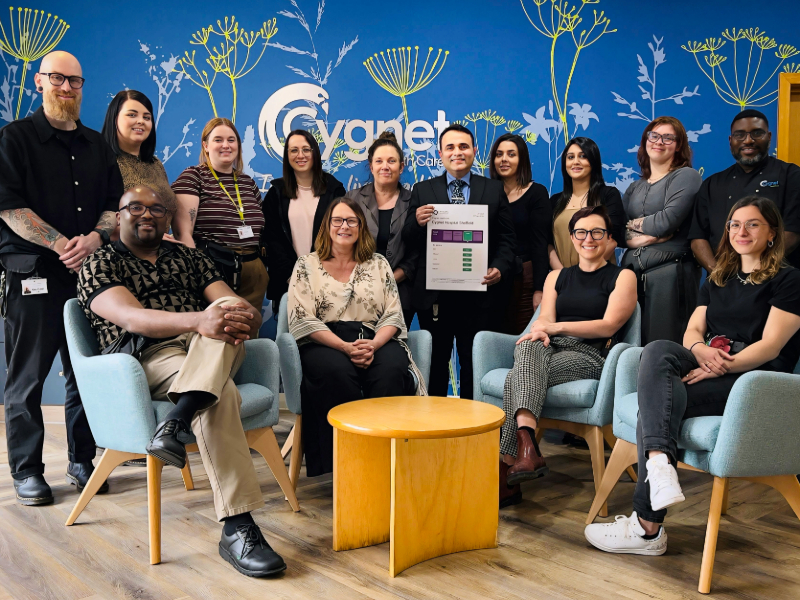 The Cygnet Hospital Sheffield team pose in the reception celebrating their recent CQC success. A man in the middle of the group holds the results.